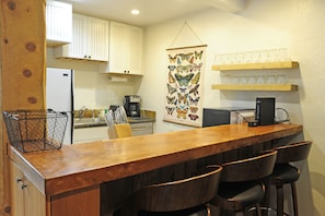 Enjoy cooking and dining in this kitchen with a bar, refrigerator, and coffee maker.