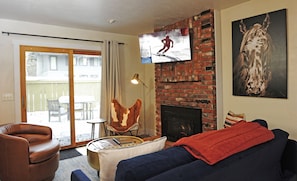 Relax in style with a comfortable sofa, coffee table, and brick fireplace, perfect for unwinding and enjoying the view from the balcony.