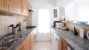 Een moderne keuken met granieten aanrechtbladen, roestvrijstalen apparatuur en houten keukenkastjes.