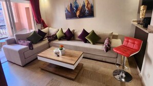 A modern living room with a sofa, a coffee table, and a red bar stool. - Appartement PATIO GUELIZ (Marrakech)