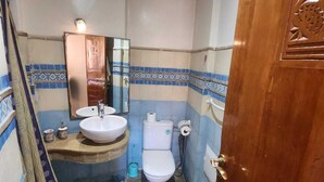 A compact bathroom with a sink, toilet, and mirror. - Appartement PATIO GUELIZ (Marrakech)