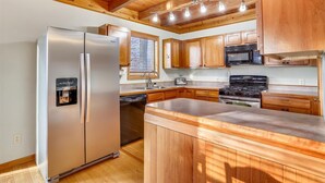 Una cocina moderna con armarios de madera, un refrigerador de acero inoxidable, un microondas y una estufa.
