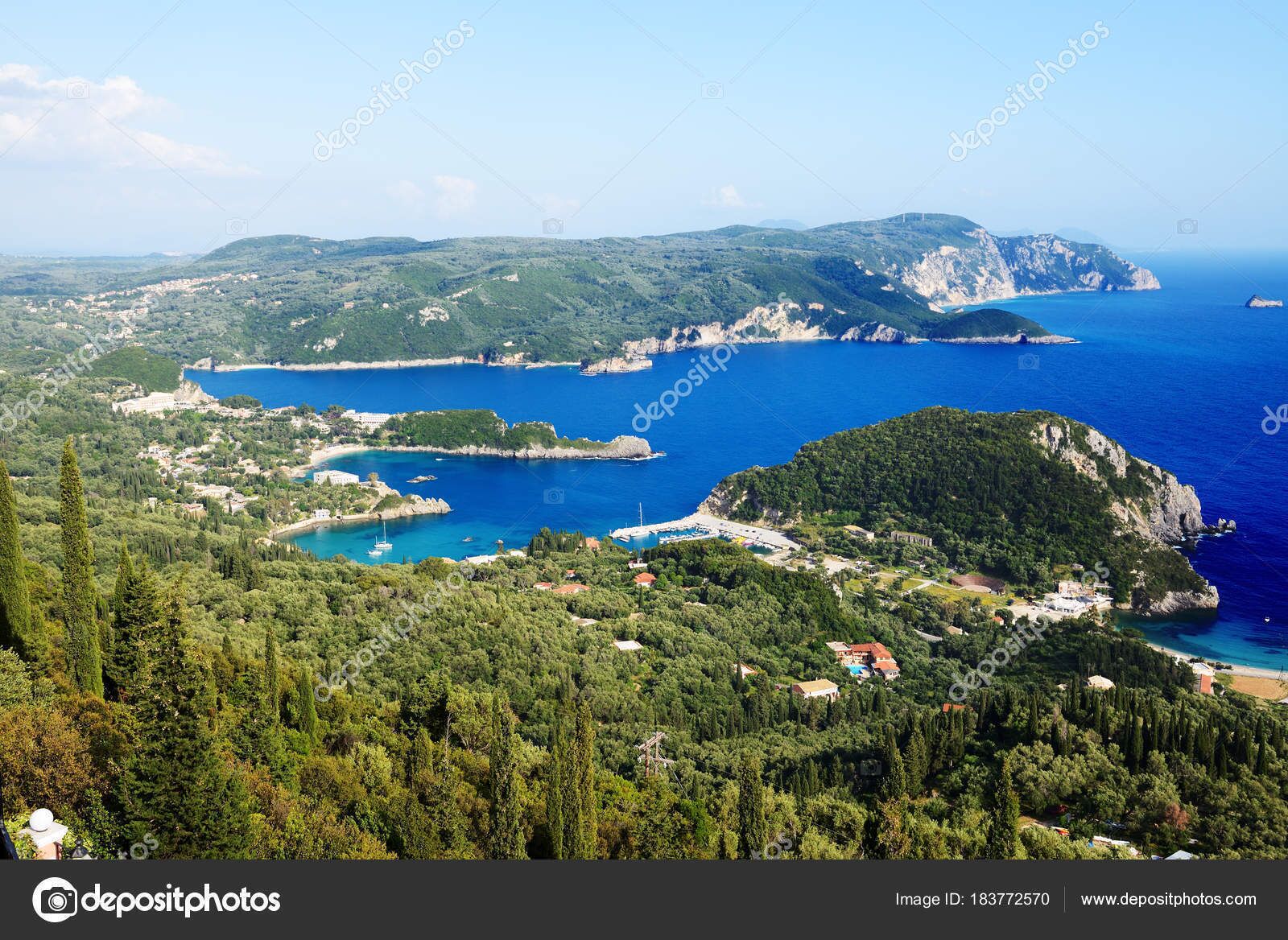 A coastal landscape with a bay, rocky cliffs, and a small settlement with buildings and greenery.