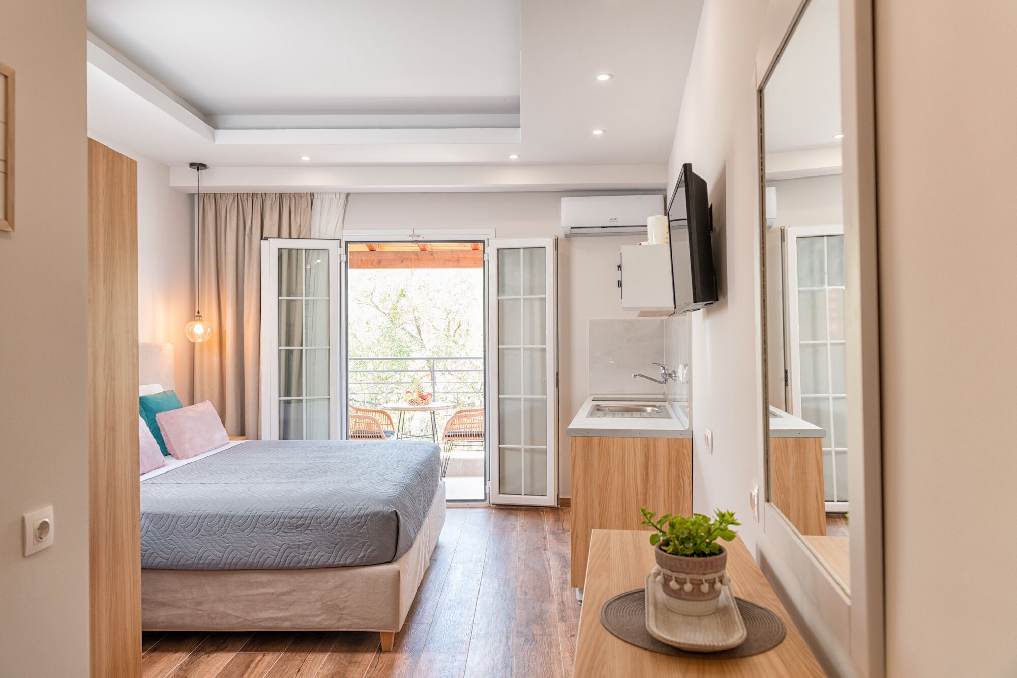 Een moderne hotelkamer met een bed, een klein kitchenette, een badkamer en een balkon met uitzicht.