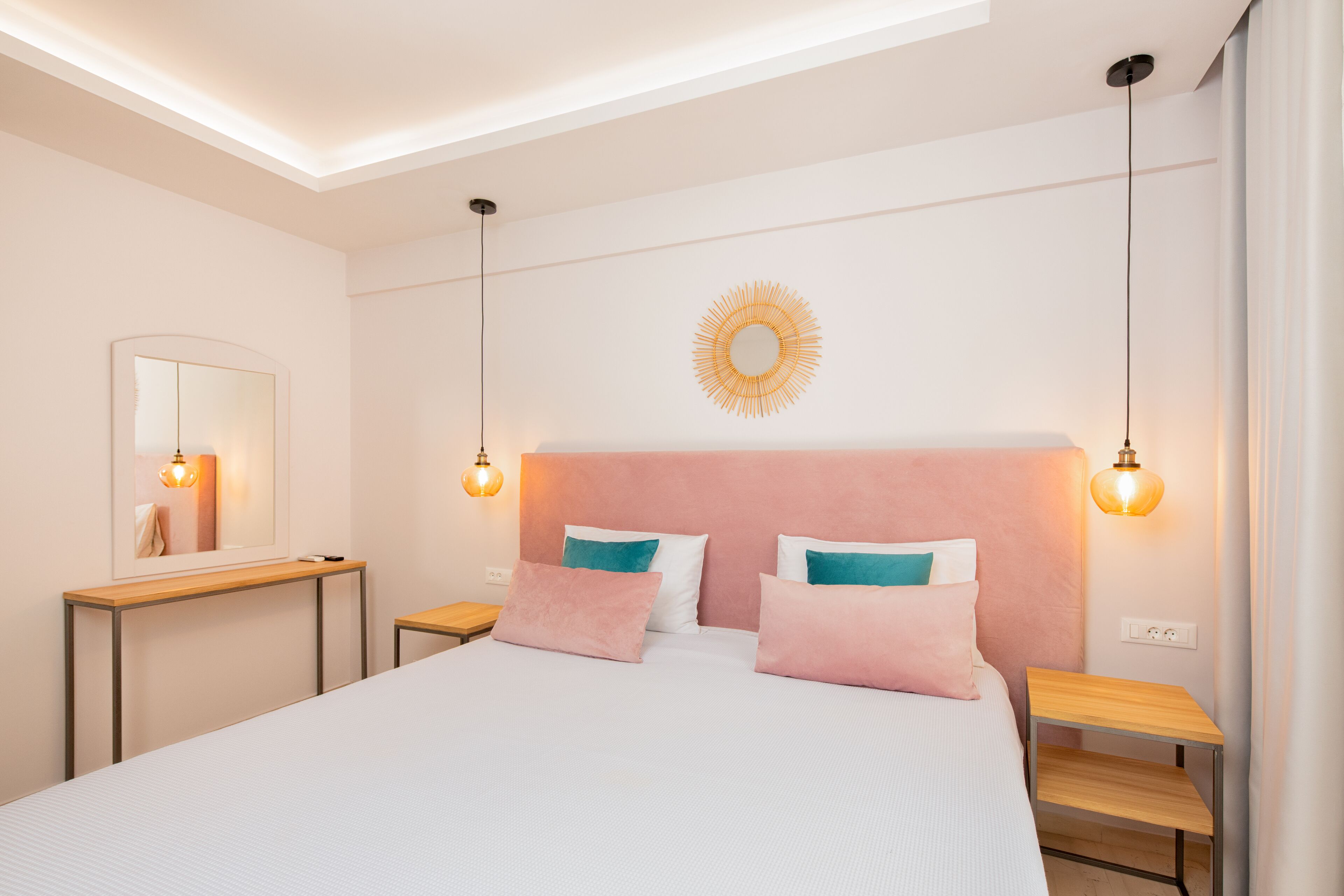 Een moderne slaapkamer met een groot bed, nachtkastjes, een spiegel en een wandlamp.
