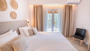A bedroom with a large bed, a chair, and a window with curtains. - Korina Apart Hotel (Corfu)