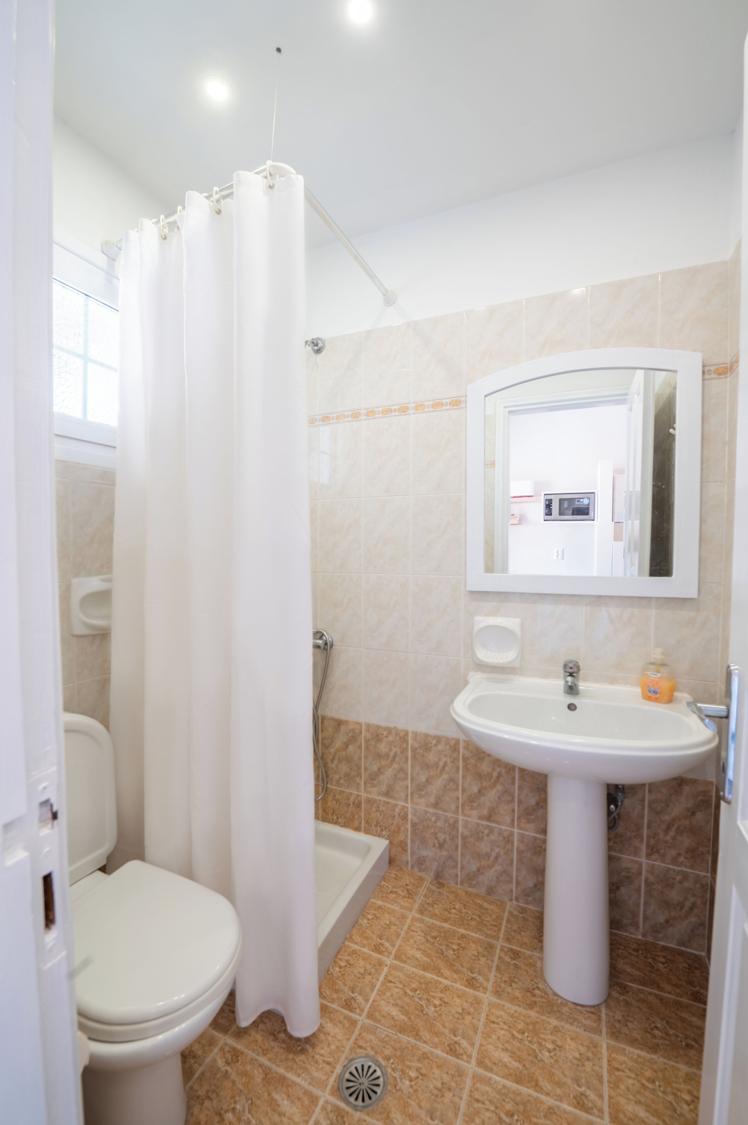 Un baño con inodoro, ducha, lavabo y espejo.