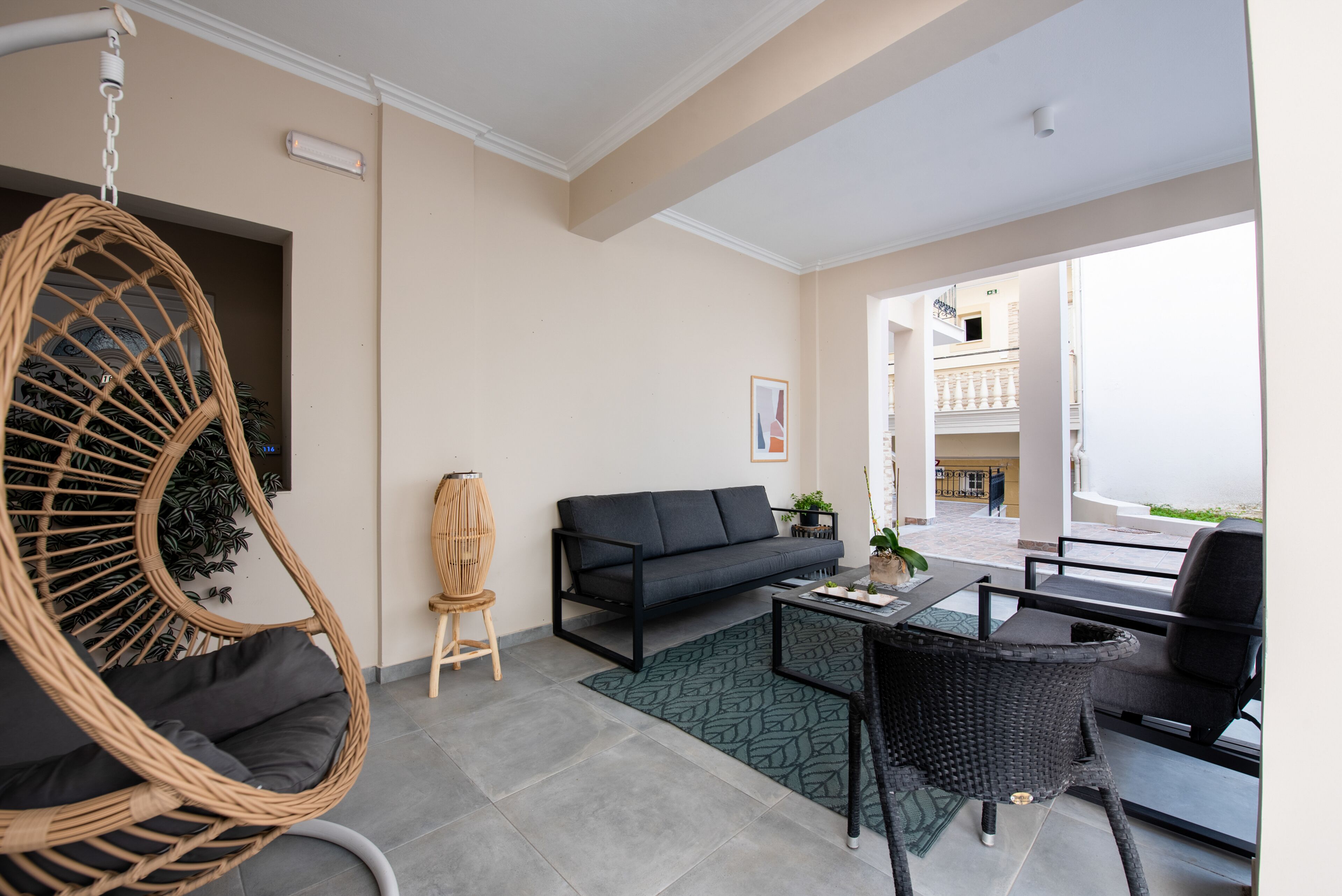 A modern living room with a hanging chair, a sofa, a coffee table, and a dining area with chairs.