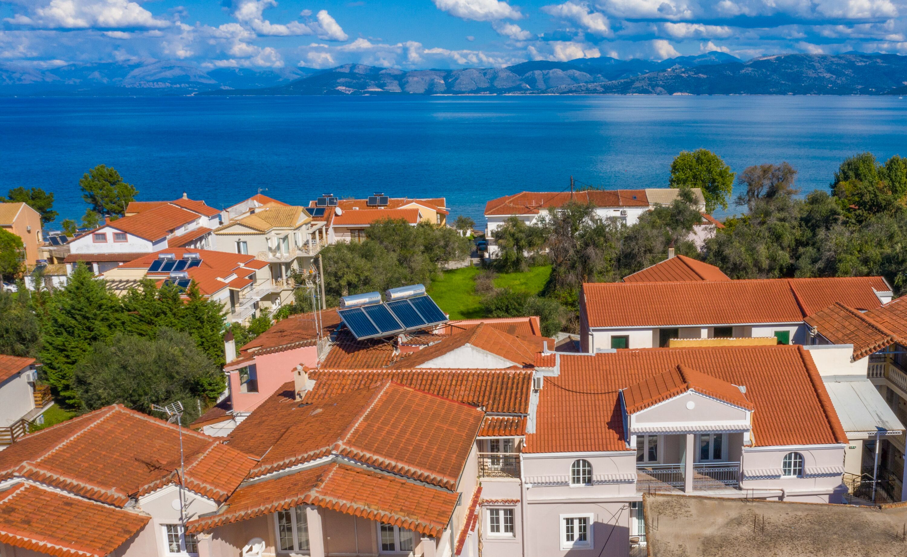 A coastal residential area with houses featuring red-tiled roofs and solar panels.