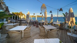 An outdoor seating area with wicker furniture and umbrellas, overlooking a body of water. - La Mar - By Almarina Villas (BENISSA)