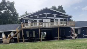 A two-story building with a balcony, wooden stairs, and a covered area with a ladder.