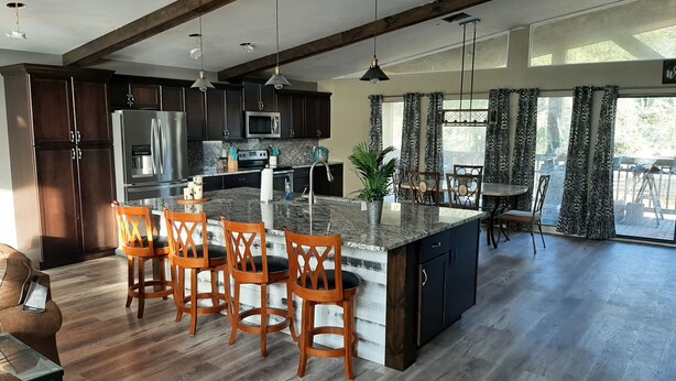 A modern kitchen with dark wood cabinets, stainless steel appliances, and a central island with bar stools.