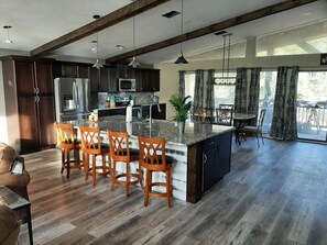 A modern kitchen with dark wood cabinets, stainless steel appliances, and a central island with bar stools.