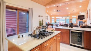 A modern kitchen with wooden cabinets, a stainless steel stove, and a large island. - Lake Time Villa I Lake Views + Hot Tub (Big Bear Lake)