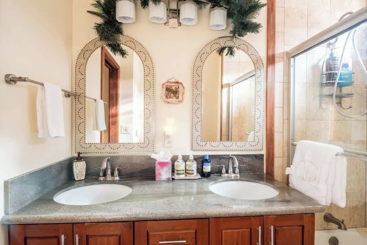 A bathroom with two sinks, a large mirror, and a shower area.