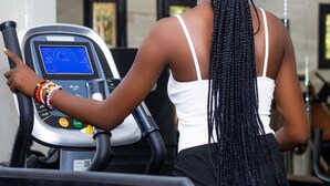 Una persona usando una cinta de correr en un gimnasio, con una pantalla digital y panel de control.