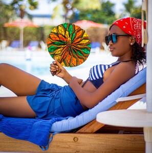 A person lounging by a poolside with a colorful fan. - Lancaster Ouaga 2000 (Ouagadougou)