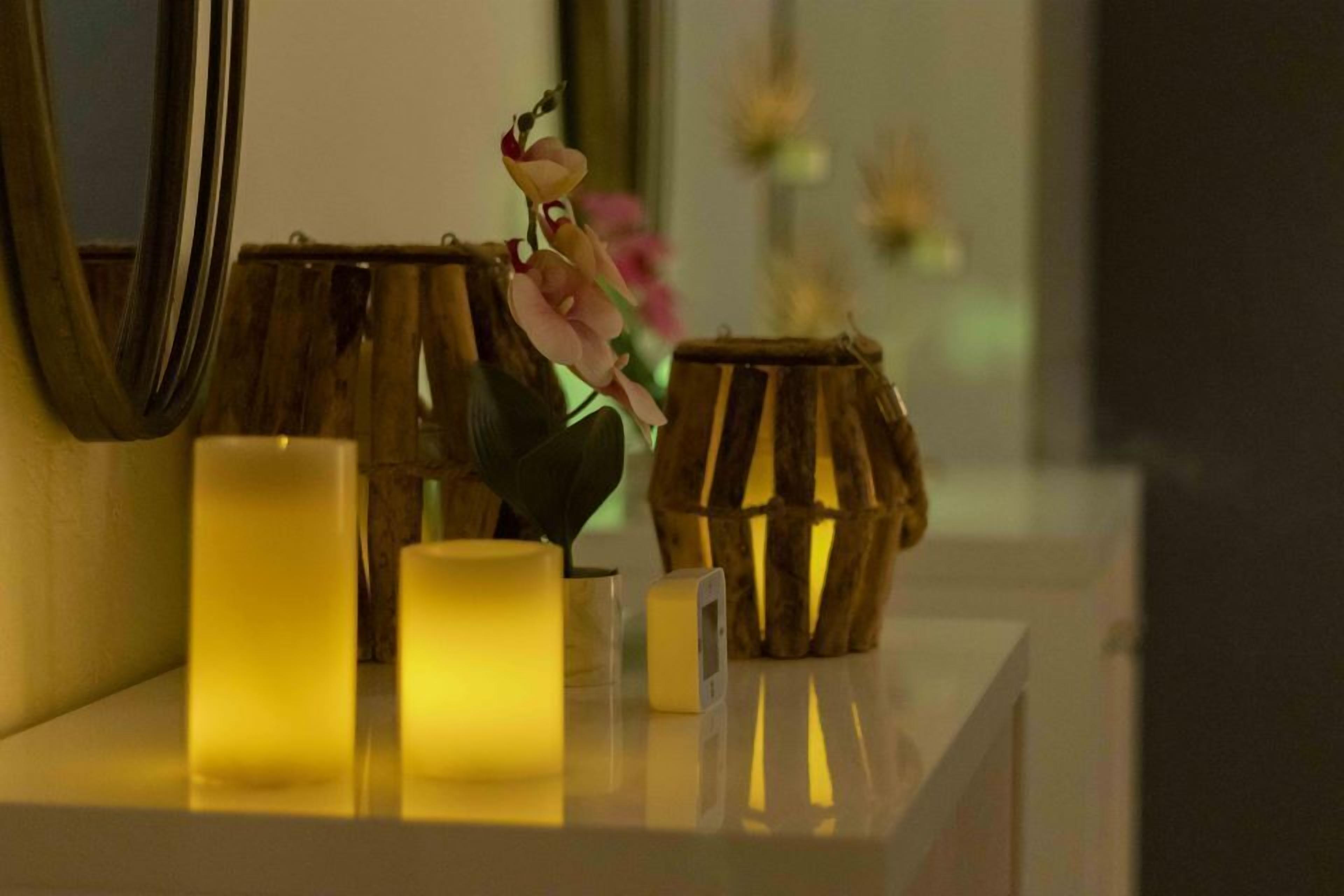 A bathroom vanity with candles, a mirror, and a vase with flowers.