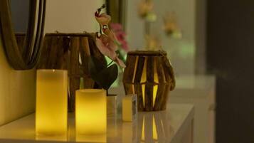 A bathroom vanity with candles, a mirror, and a vase with flowers.