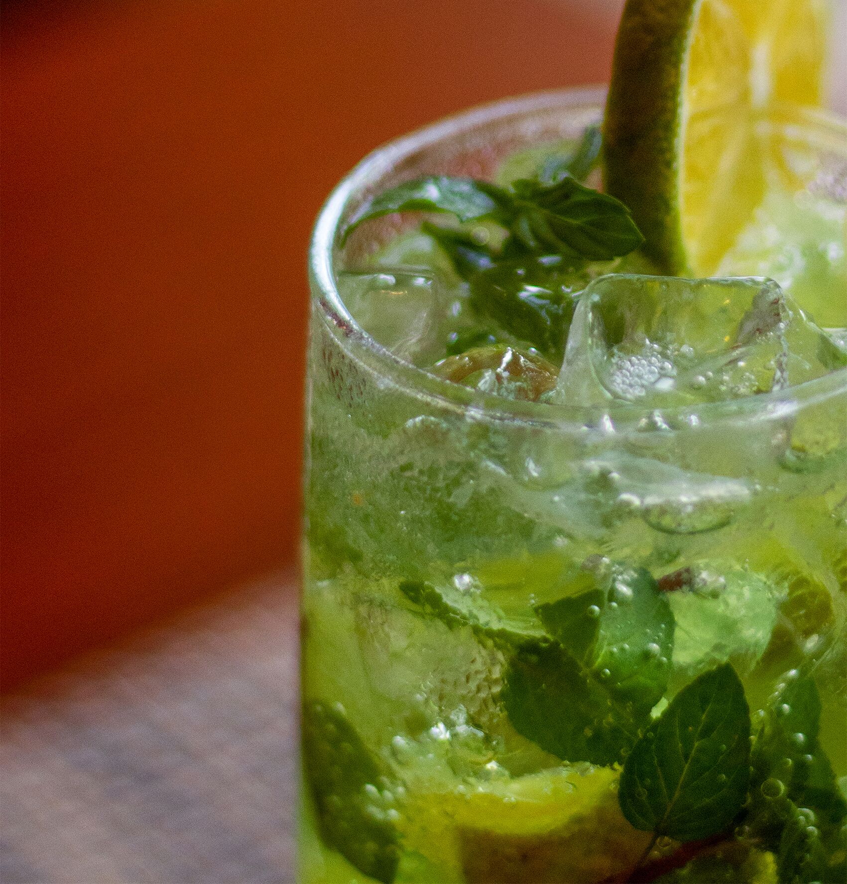 Un verre d’une boisson verte, avec des glaçons et une tranche de citron vert.