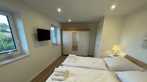 Camera d'albergo con due letti, televisione, finestra vista, armadio e comodino con lampada.