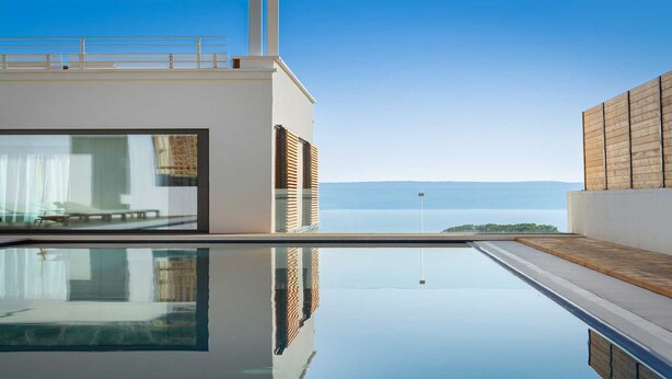 A modern infinity pool with a clear view of the sea and mountains in the background. - Villa Senzea  - modern villa with heated pool, gym, sauna, jacuzzi and sea views by MyWaycation (Marusici)