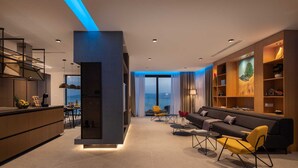 A modern living room with a sofa, chairs, a dining area, and a large window with a view. - Villa Senzea  - modern villa with heated pool, gym, sauna, jacuzzi and sea views by MyWaycation (Marusici)