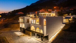 A modern two-story building with multiple balconies, large windows, and a well-lit entrance. - Villa Senzea  - modern villa with heated pool, gym, sauna, jacuzzi and sea views by MyWaycation (Marusici)