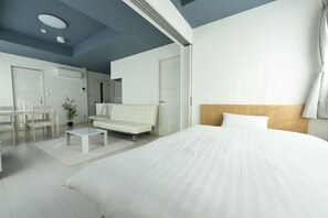 Una habitación de hotel moderna con una cama grande, un sofá, una mesita y un escritorio.