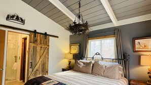 Ein Schlafzimmer mit einem großen Bett, einer Kristalllüster, einer Holztür und einem Vorhangfenster.