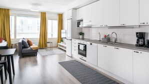 Moderni keittiö, jossa on valkoiset kaapit, sisäänrakennettu uuni ja kahvinkeitin.