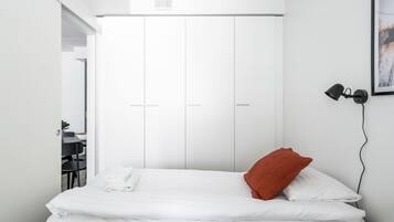 Ett sovrum med en säng, en vit garderob och ett skrivbord med en stol.