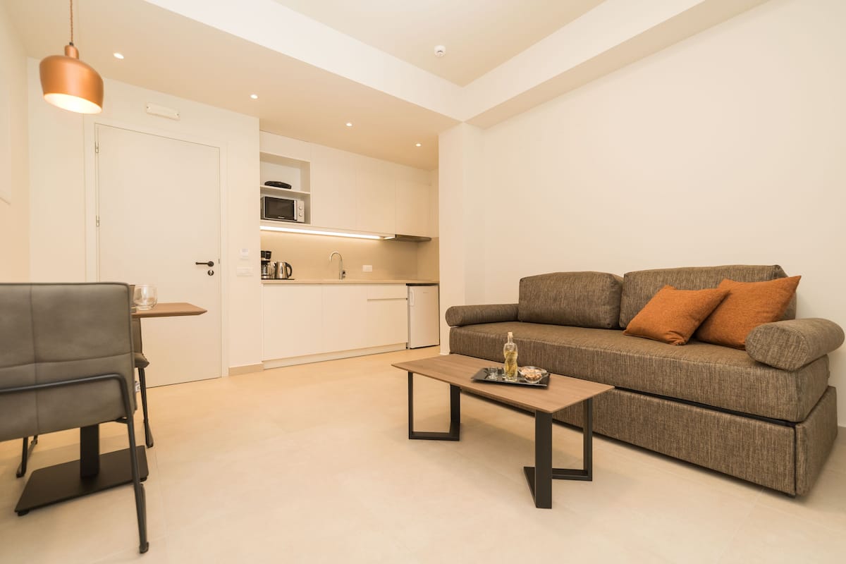 A modern living room with a sofa, a coffee table, and a dining area.