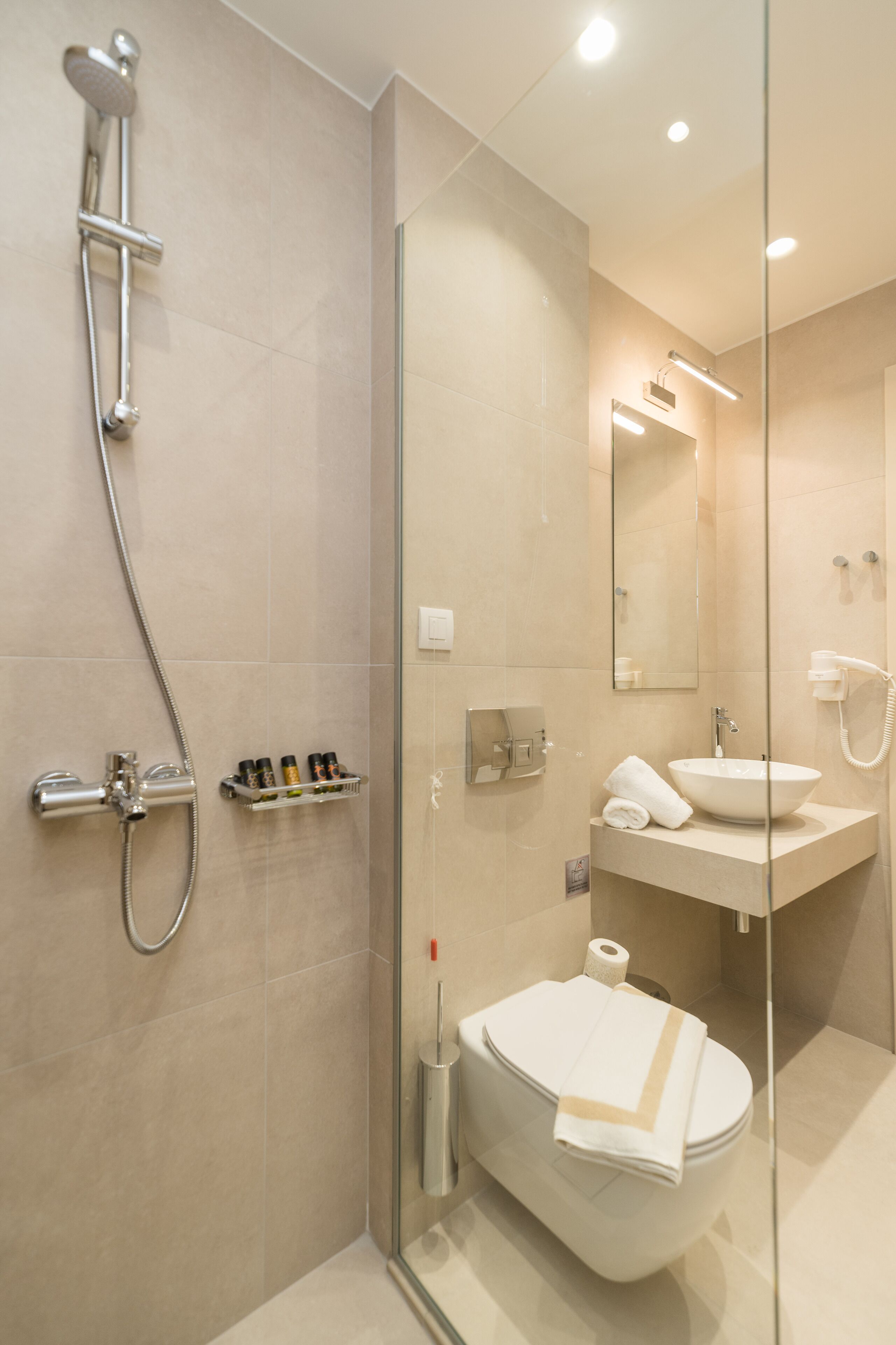 Un baño moderno con ducha de vidrio, lavamanos blanco y un inodoro.