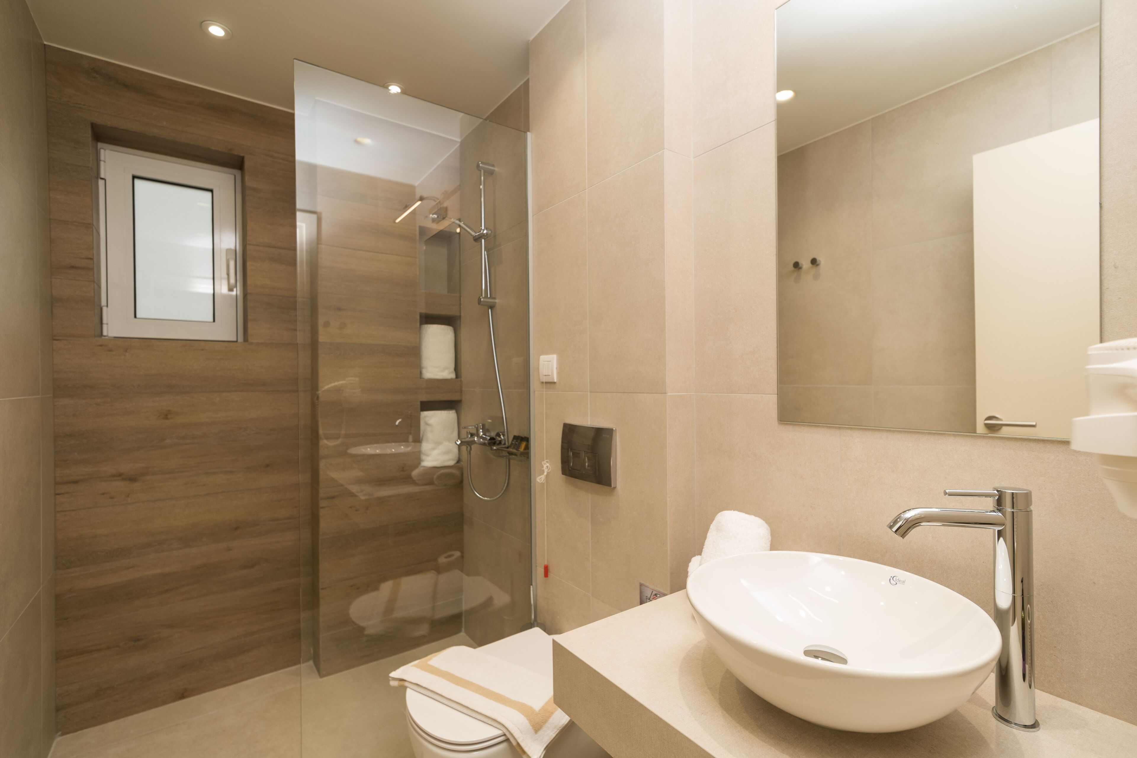 A modern bathroom with a glass shower enclosure, a large sink, and a mirror.