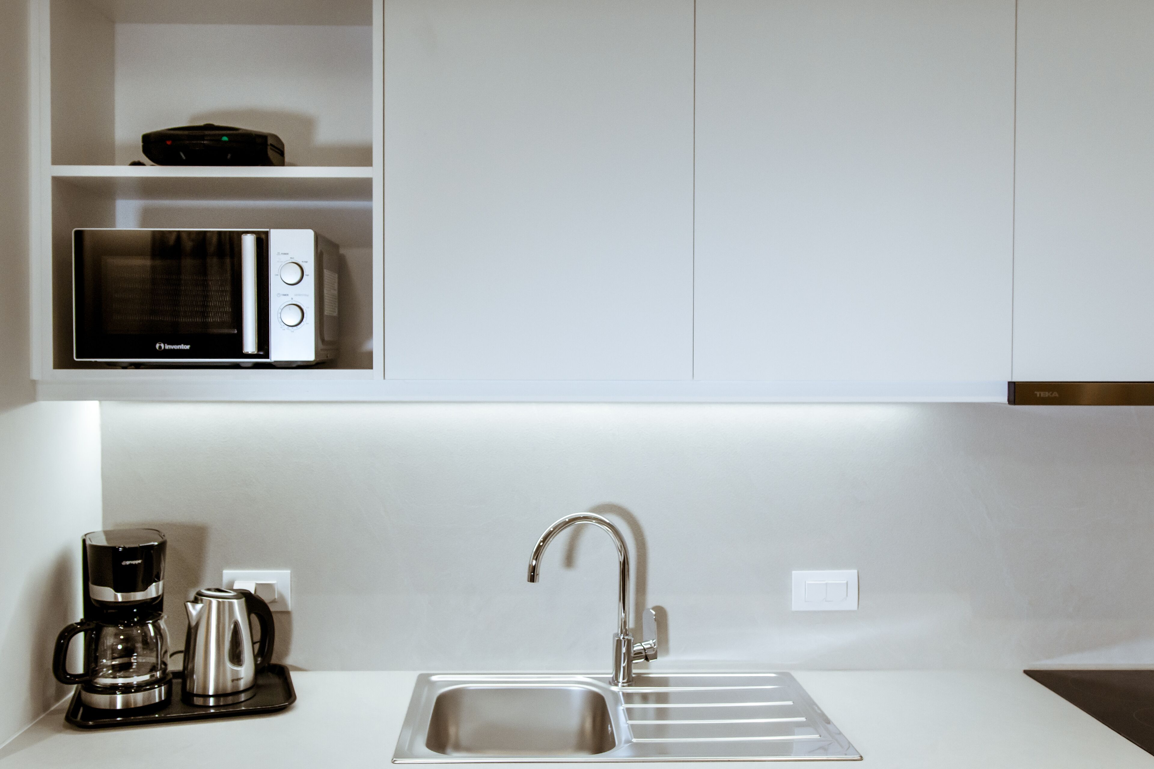 A modern kitchen with a built-in microwave, coffee maker, and sink.