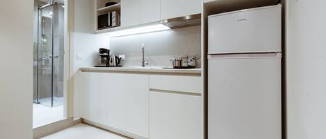 A modern kitchen with white cabinets, a built-in oven, and a coffee maker.