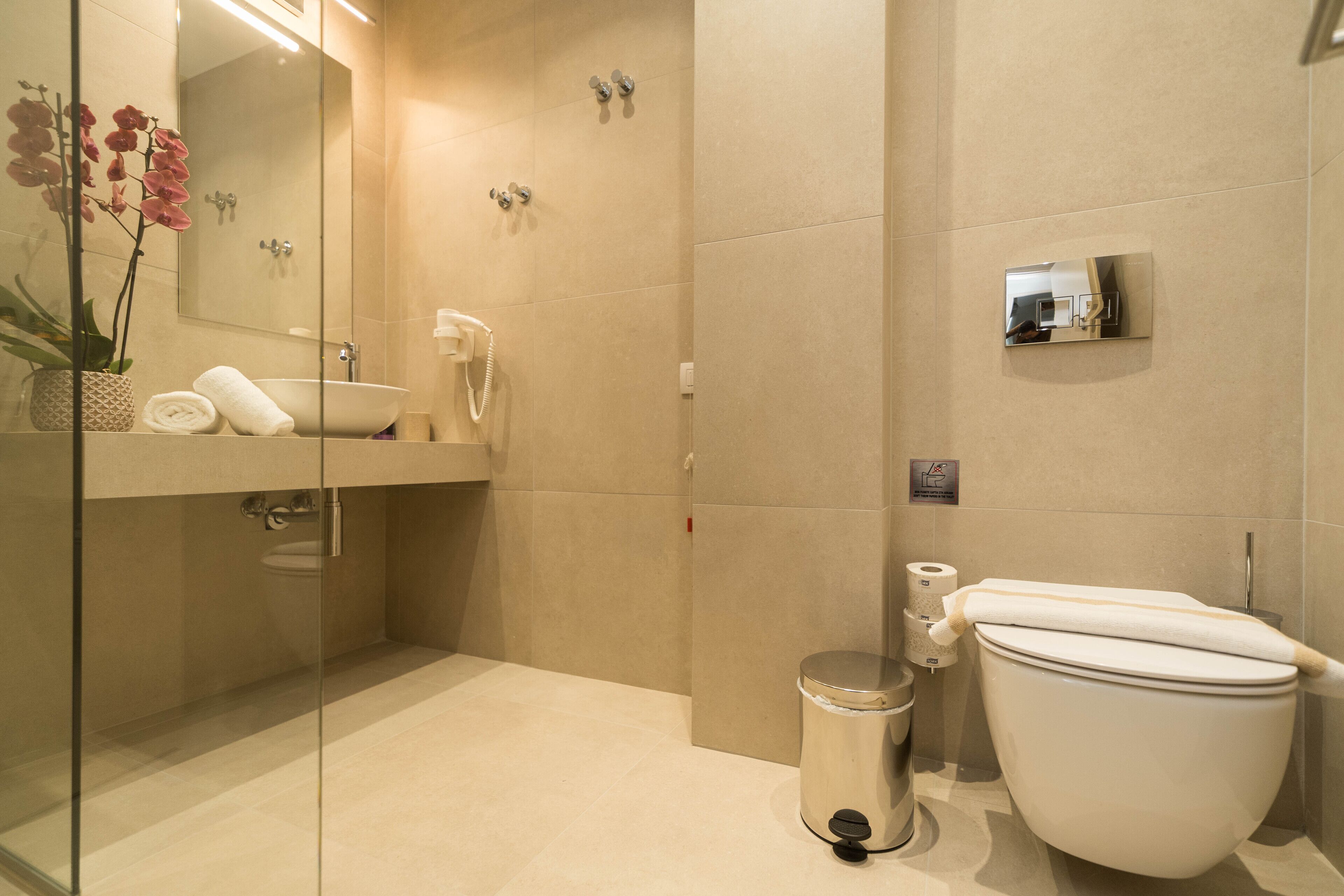 Un baño moderno con ducha de vidrio, lavamanos blanco y retrete.