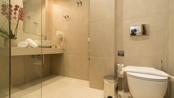 Un baño moderno con ducha de vidrio, lavamanos blanco y retrete.