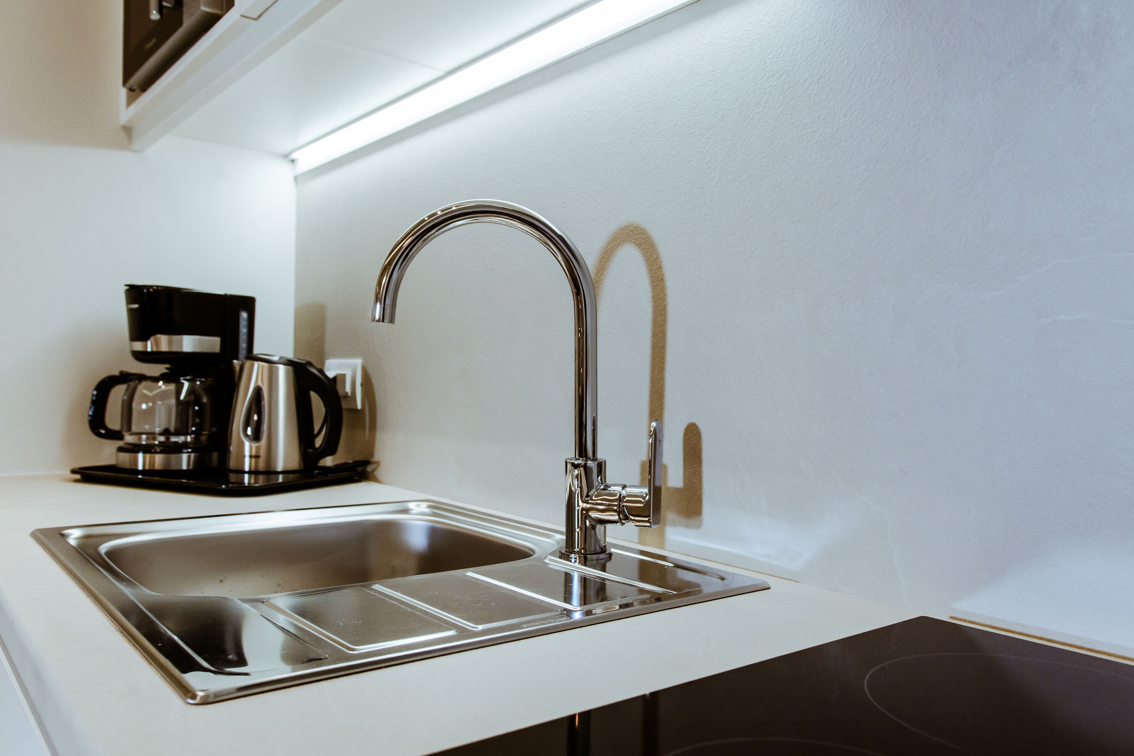 Une cuisine moderne dotée d’un évier en acier inoxydable, d’une machine à café et d’un robinet élégant.