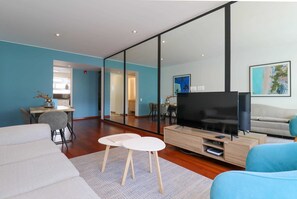 A modern living room with a flat-screen TV, a sofa, a coffee table, and a dining area with chairs. - w* | Amazing 2BR near Malecon in Miraflores (Miraflores)