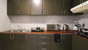 Une cuisine avec des meubles de couleur sombre, un four à micro-ondes, une bouilloire et une cuisinière à gaz.