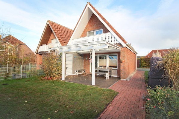 A two-story house with a balcony, a covered patio, and a fenced backyard.