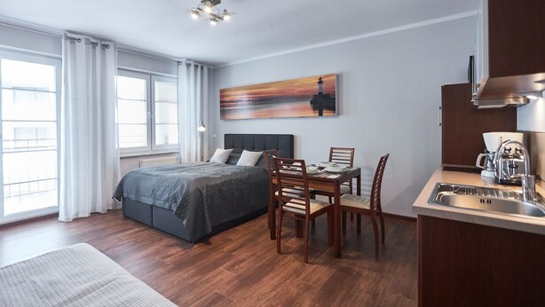 Una habitación de hotel moderna con cama, mesa de comedor y zona de cocina.
