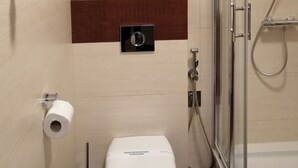 A bathroom with a glass shower enclosure, a toilet, and a towel rack with two towels. - Apartamenty Swinoujscie - Villa Park (Swinoujscie)