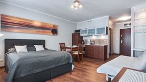 A compact room with a bed, a small dining table, a kitchenette, and a glass display cabinet. - Apartamenty Swinoujscie - Villa Park (Swinoujscie)