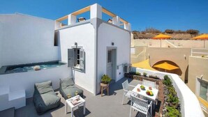 A rooftop terrace with a hot tub, outdoor seating, and a dining area. - Aetheria Villas (Santorini)