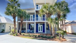 A two-story residential building with a balcony, surrounded by palm trees and a well-maintained lawn. - Steps to Pvt beach/Beach ramp/2 pools/Sleeps 18 (Miramar Beach)