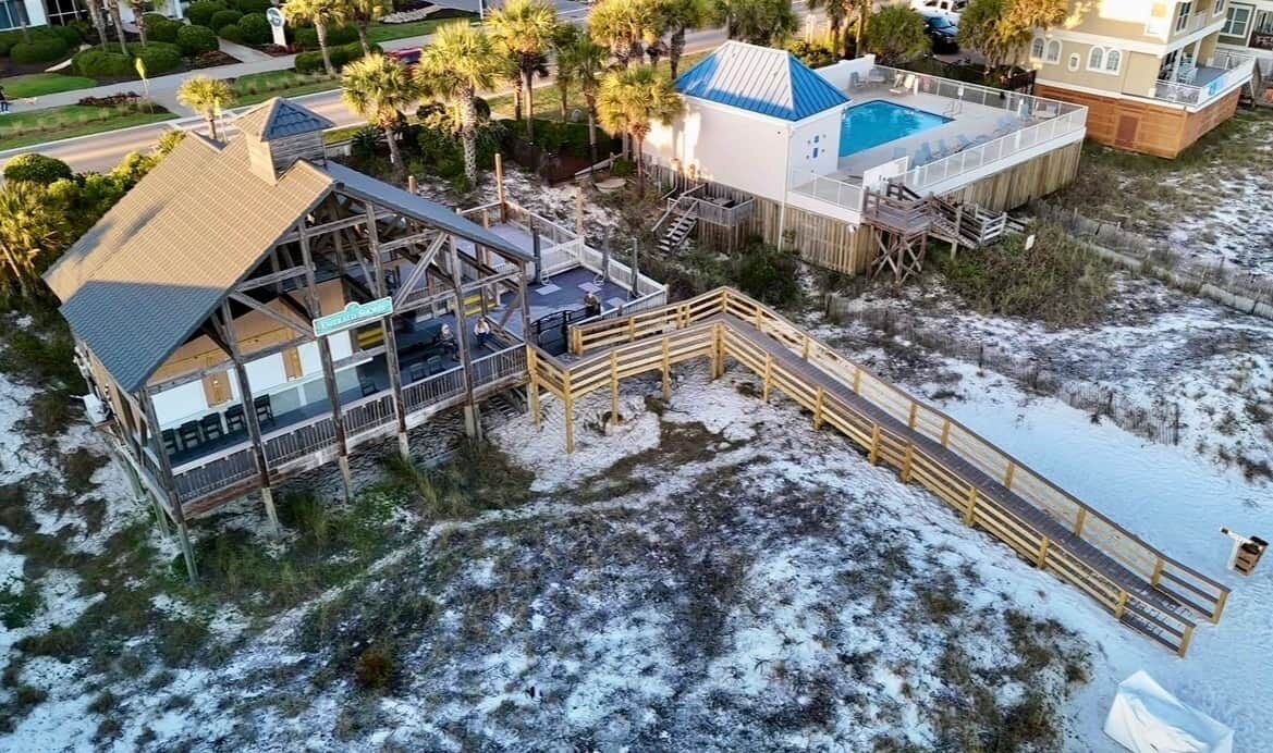 A beachfront property with a pool, wooden deck, and a covered area.