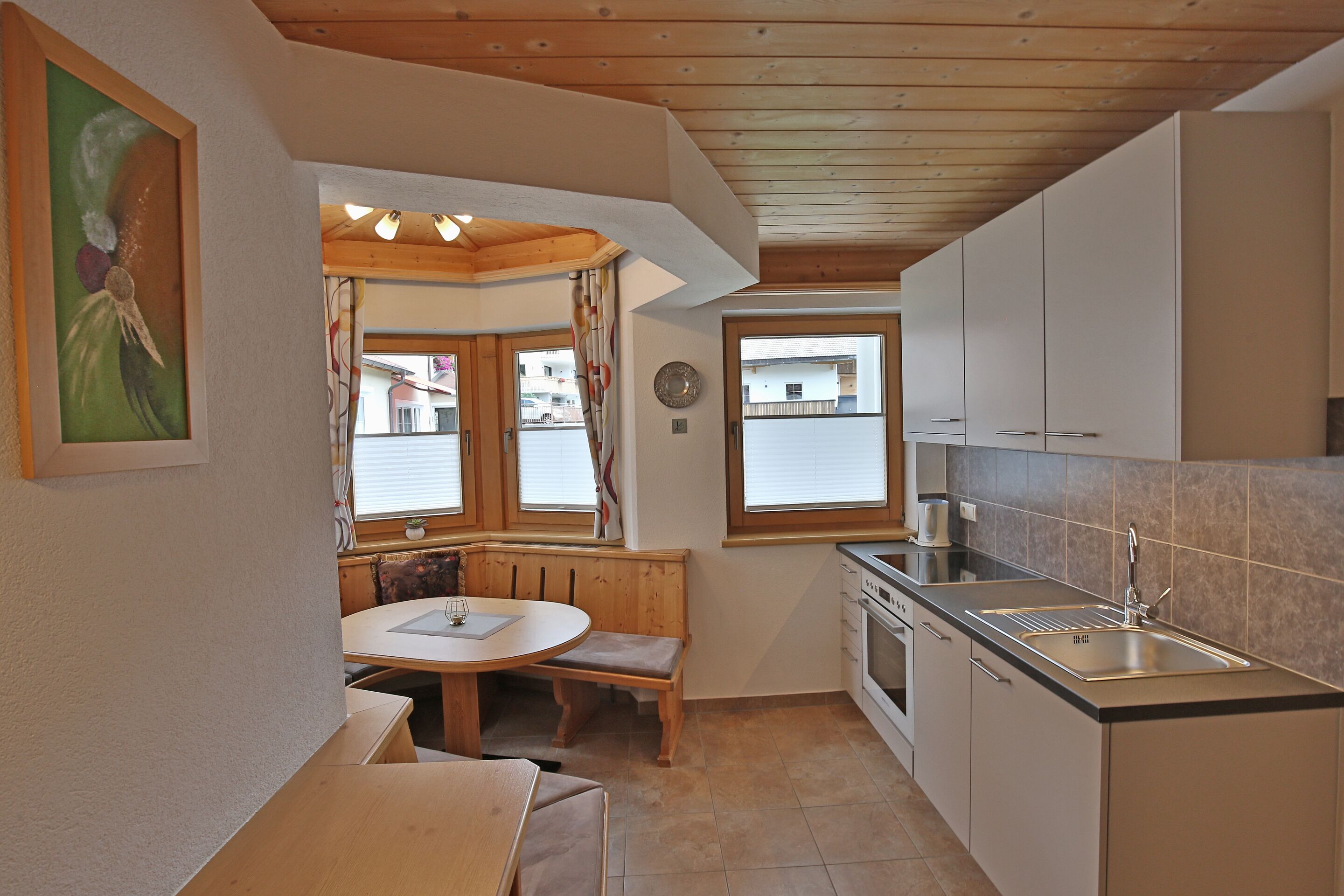 A compact kitchen with a wooden bench, a sink, and cabinets.